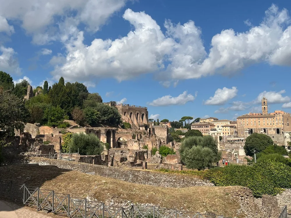 The Palatine Hill ruins under a bright summer sky with white clouds