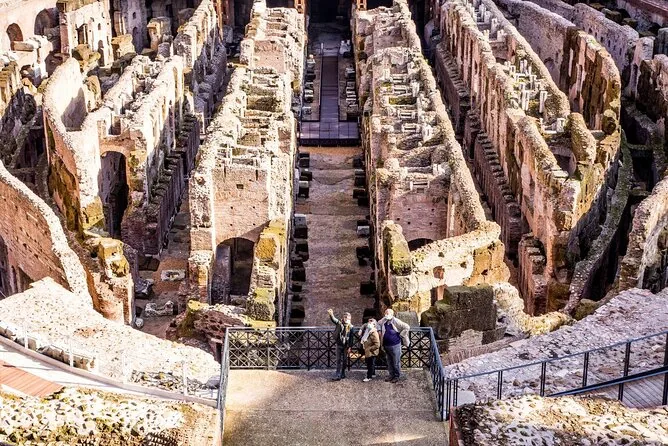 Visitors on a walkway between the stone walls of the Colosseum hypogeum, seen from above