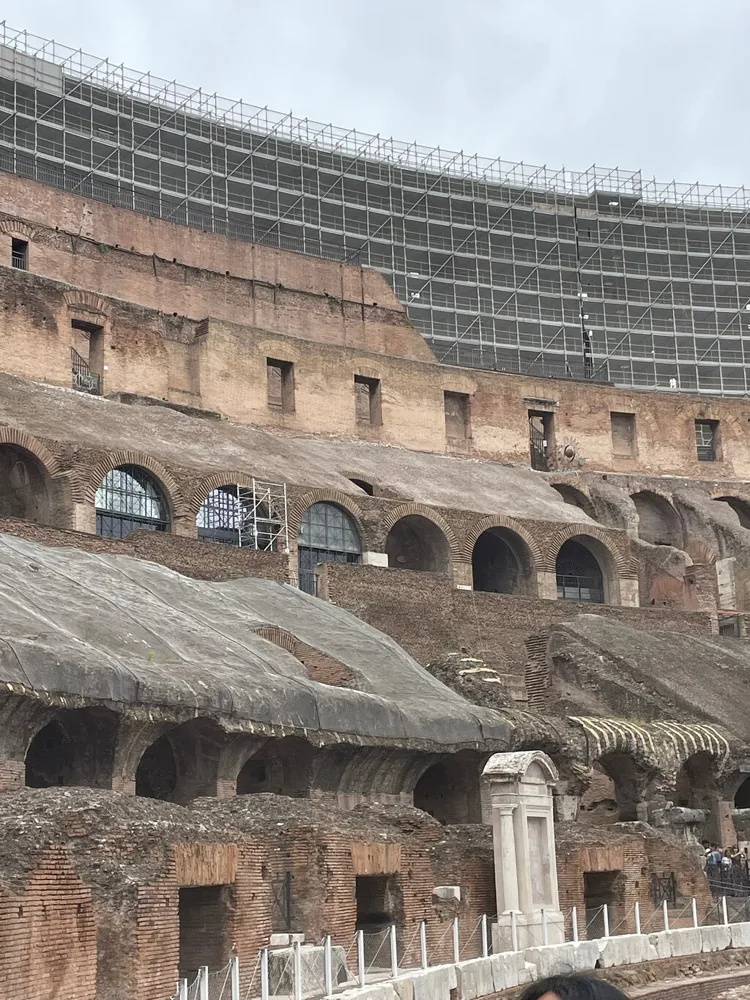 The upper arches of the Colosseum interior in soft morning light, with a cloudy sky above